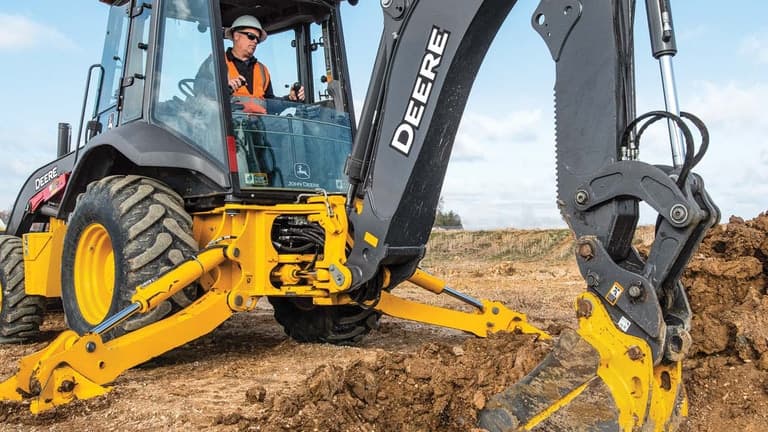 A close-up of an operator using the 310P-Tier Backhoe to scoop dirt. | 4re Equipment