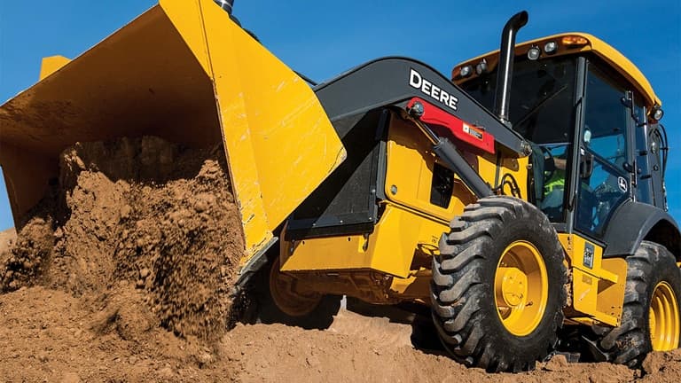A 310P Backhoe dumping dirt from the bucket. | 4re Equipment