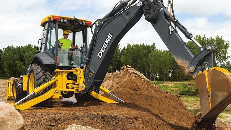 An operator using a 710P-Tier Backhoe to dump dirt in a trench. | 4re Equipment
