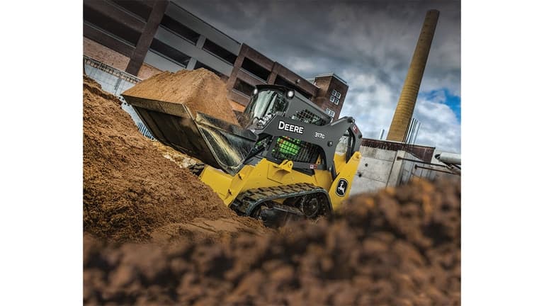 A 317G Compact Track Loader scooping dirt at a worksite. | 4re Equipment