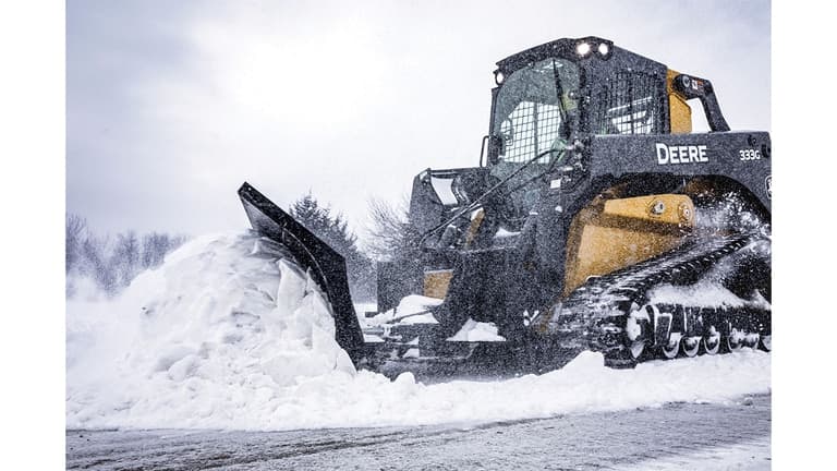A 333G Compact Track Loader with snow blade attachment plowing snow. | 4re Equipment