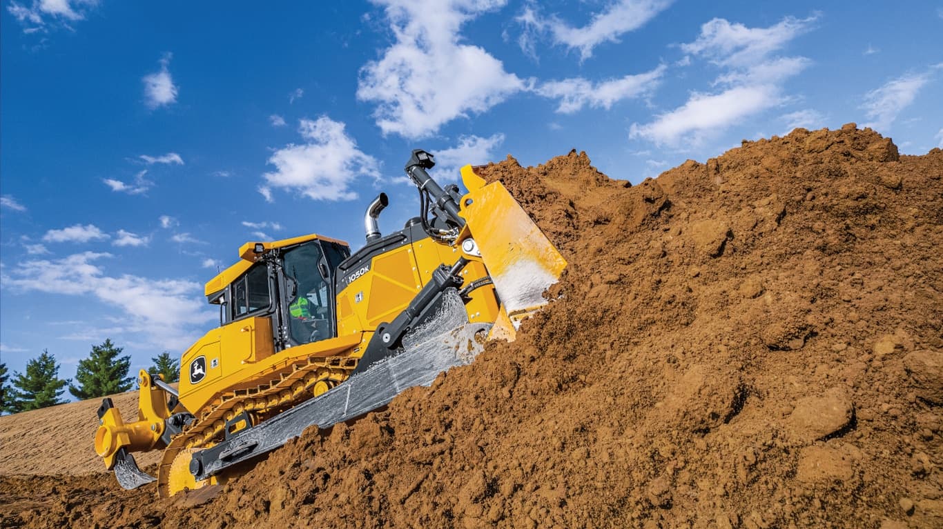 A 1050K Dozer pushing dirt on a hill at a worksite. | 4re Equipment | ID: 1050kt