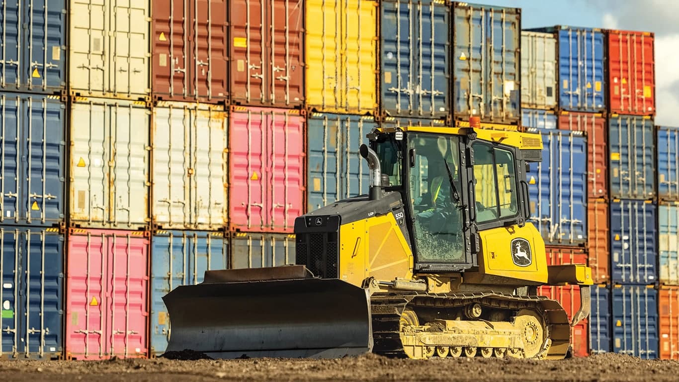 550P Dozer in front of a wall of colorful shipping containers. | 4re Equipment | ID: 550PFT4