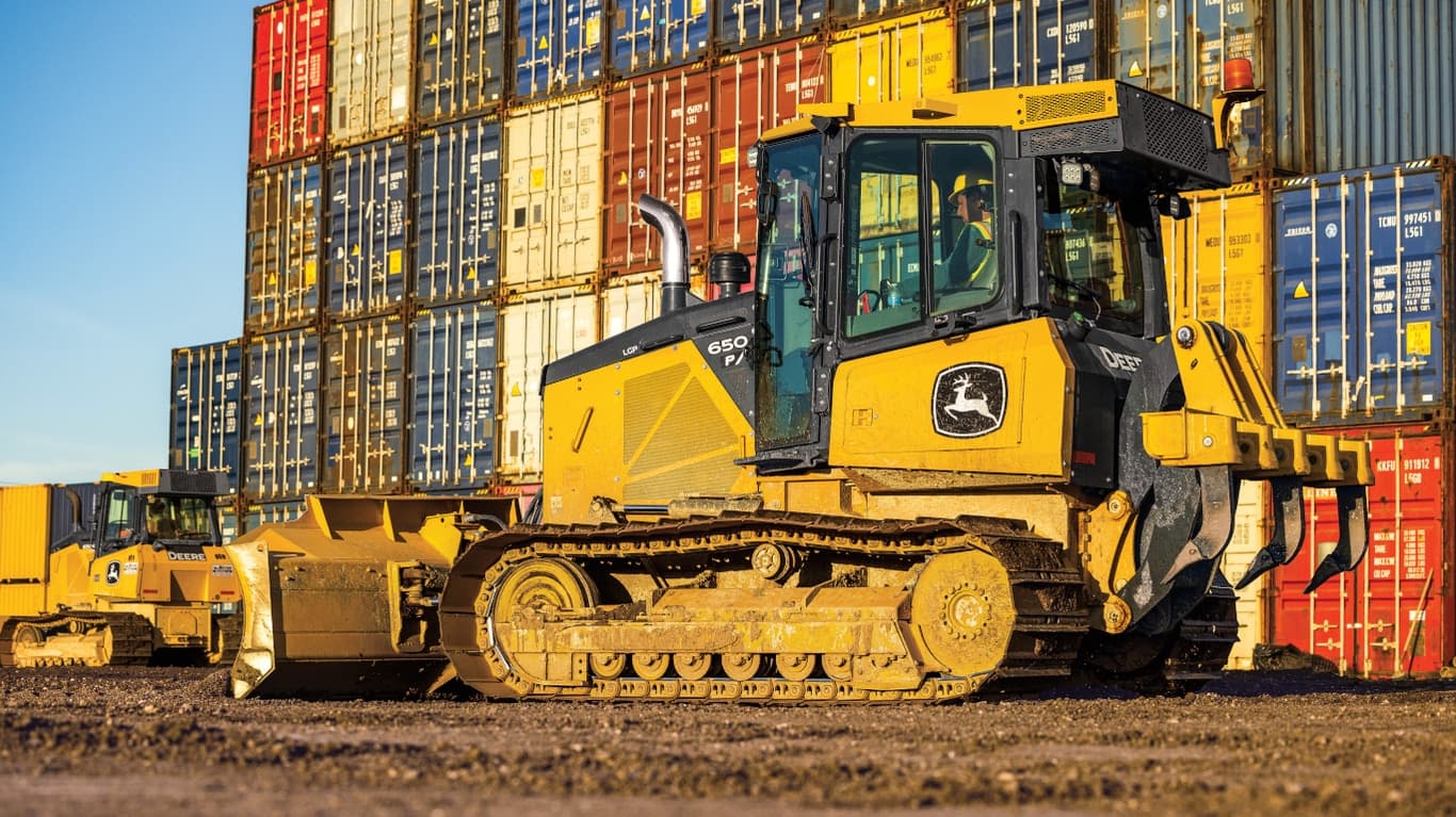 Left-side view of a 650P Dozer in front of a wall of colorful shipping containers. | 4re Equipment | ID: 650PFT4