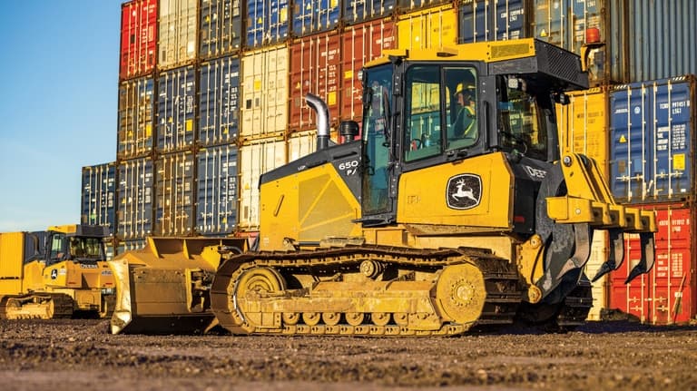 Left-side view of a 650P Dozer in front of a wall of colorful shipping containers. | 4re Equipment