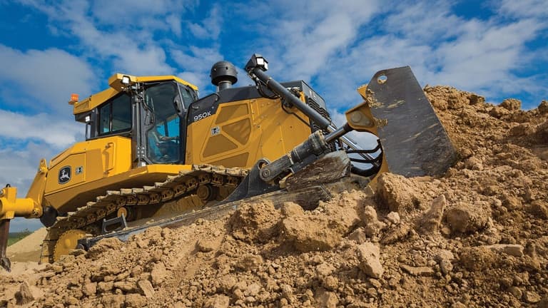 A close-up of a 950K Dozer pushing dirt on top of a stockpile. | 4re Equipment