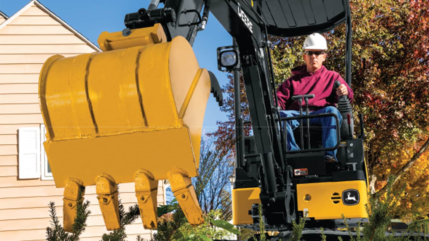 A close up of the 17P-Tier Excavator bucket hovering above plants with an operator and house in the background. | 4re Equipment | ID: 17PEXFT4
