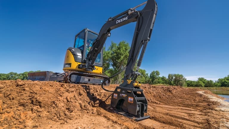 A 35G Excavator with a PC7 plate compactor attachment compacting dirt on a worksite. | 4re Equipment