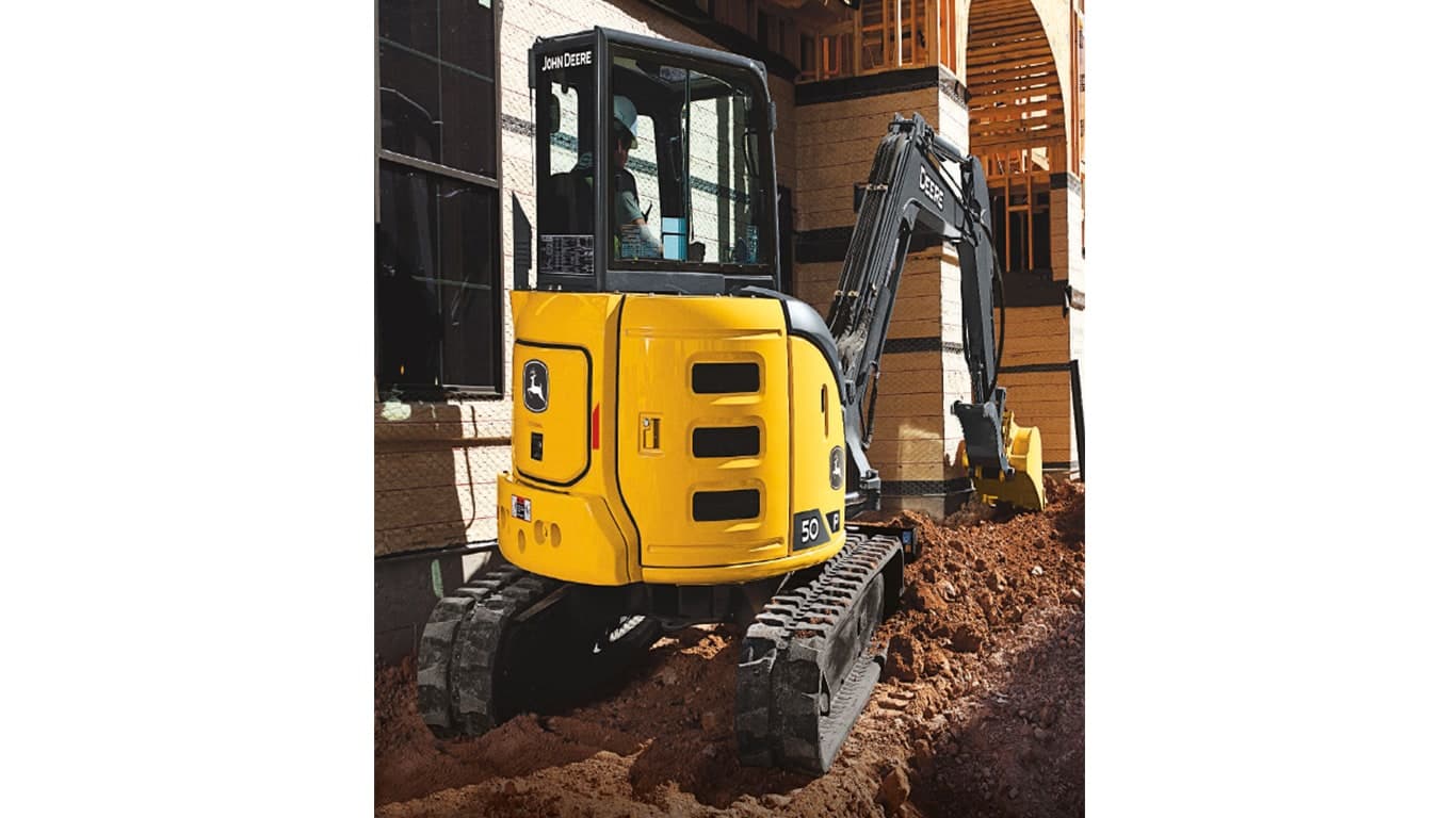 The back side of a 50 P-Tier Excavator moving dirt at a worksite with a building in the background. | 4re Equipment | ID: 50PEXFT4