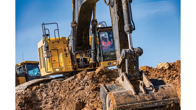 An operator using a 670P-Tier Excavator to scoop up dirt at a worksite. | 4re Equipment