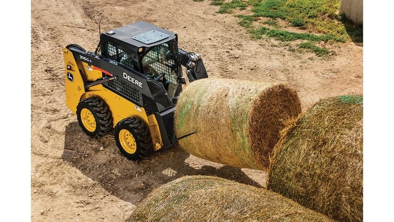 A 316G Skid Steer with bale spear attachment moving a hay bale. | 4re Equipment